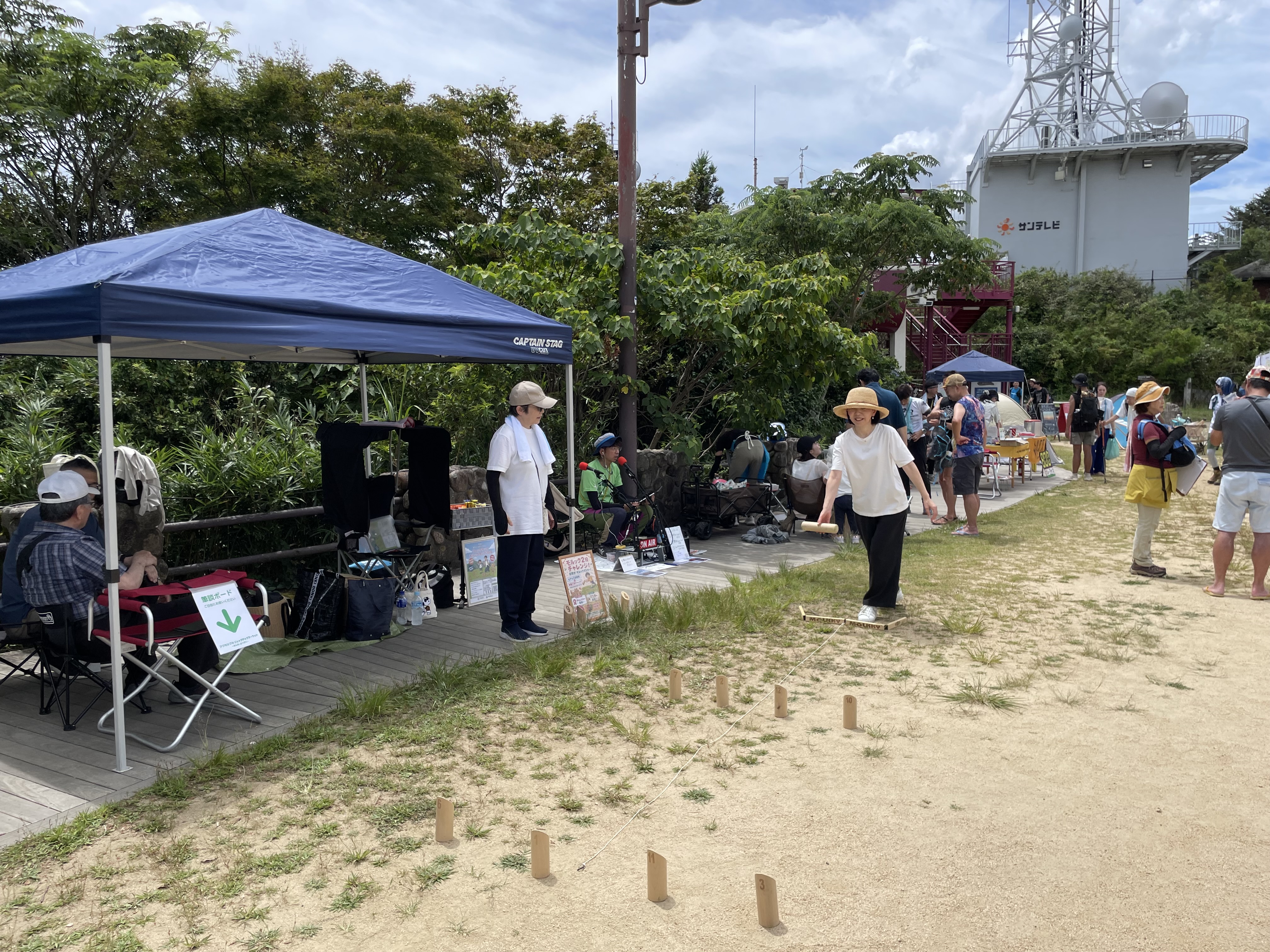 摩耶山掬星台のモルック2投チャレンジ会場。テントの前で並んだスキットルに向かってモルックを投げる参加者
